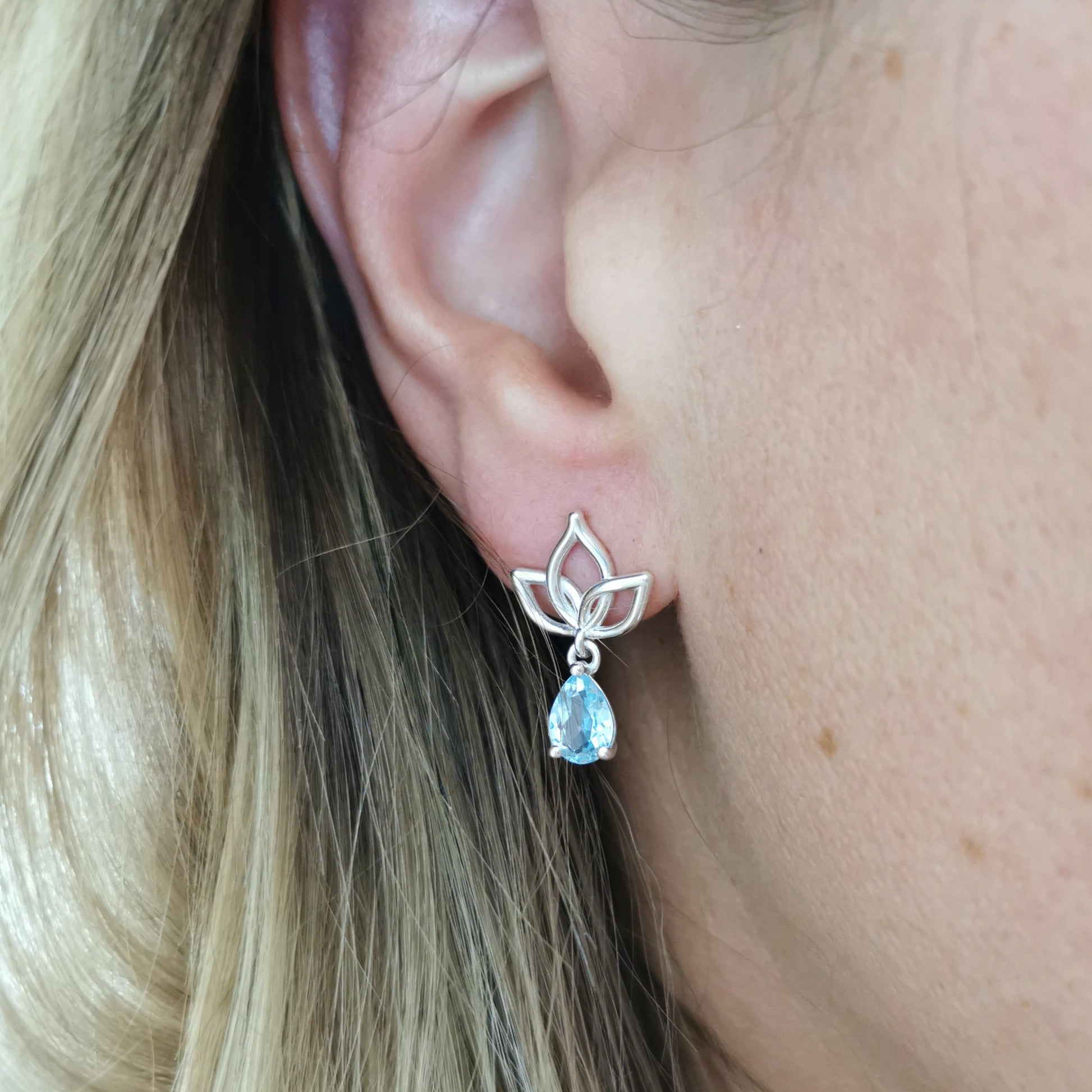 Pear Cut Sky Blue Topaz Silver Lotus Earrings on the ear.